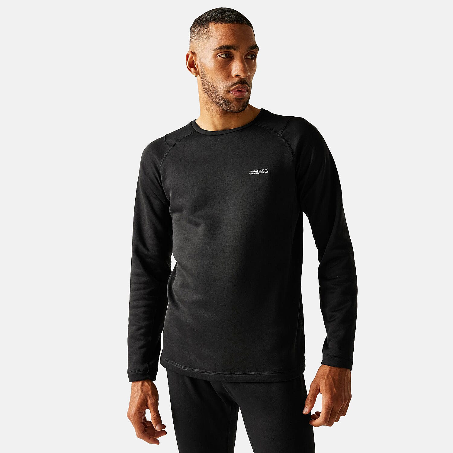 Man wearing black long-sleeve crewneck sweatshirt with small chest logo and black pants