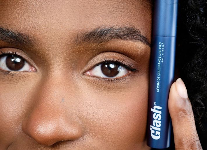 Gros plan sur l'oeil d'une femme appliquant un stylo de mascara bleu foncé