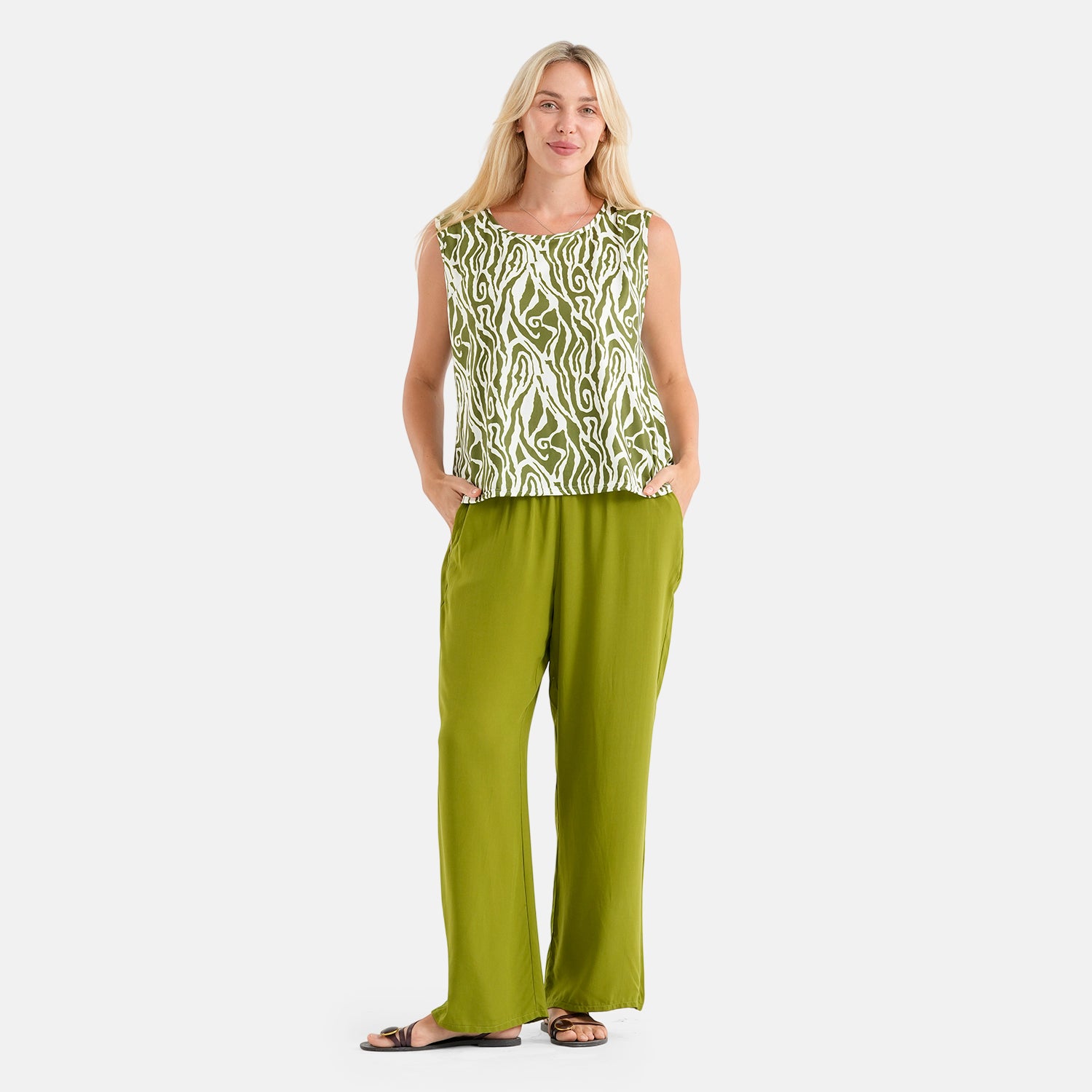Woman wearing green and white zebra-striped sleeveless top with matching green wide-leg pants and brown sandals