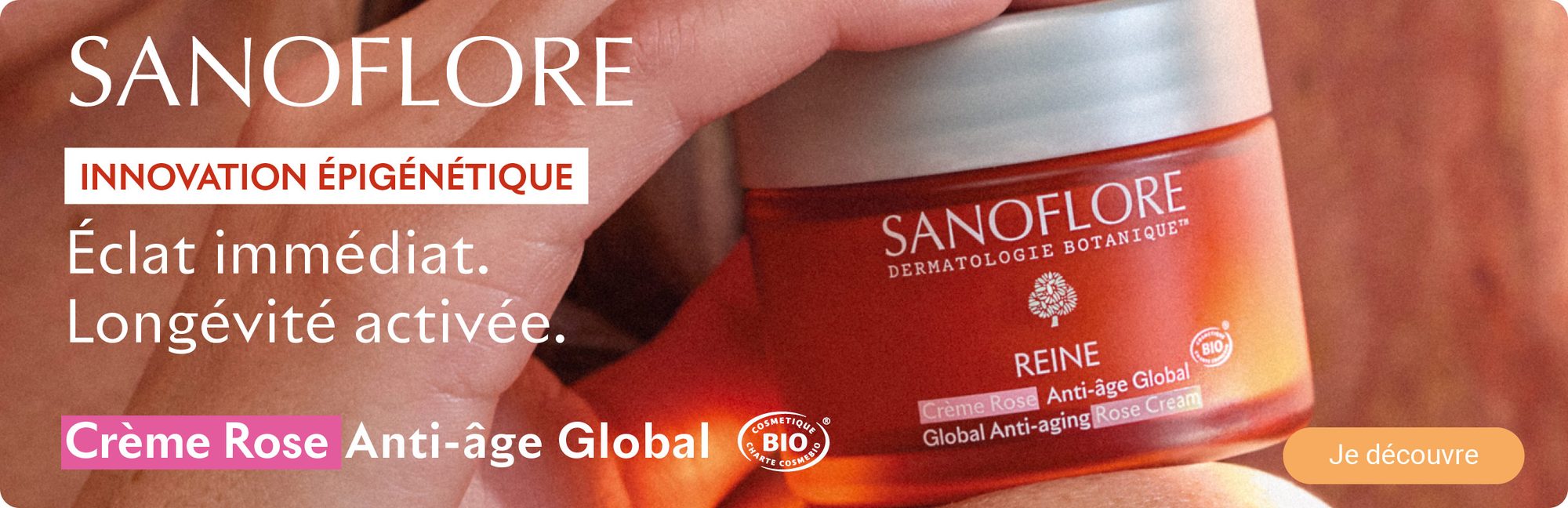 Crème rose anti-âge global dans un pot en verre rouge et blanc tenue à la main