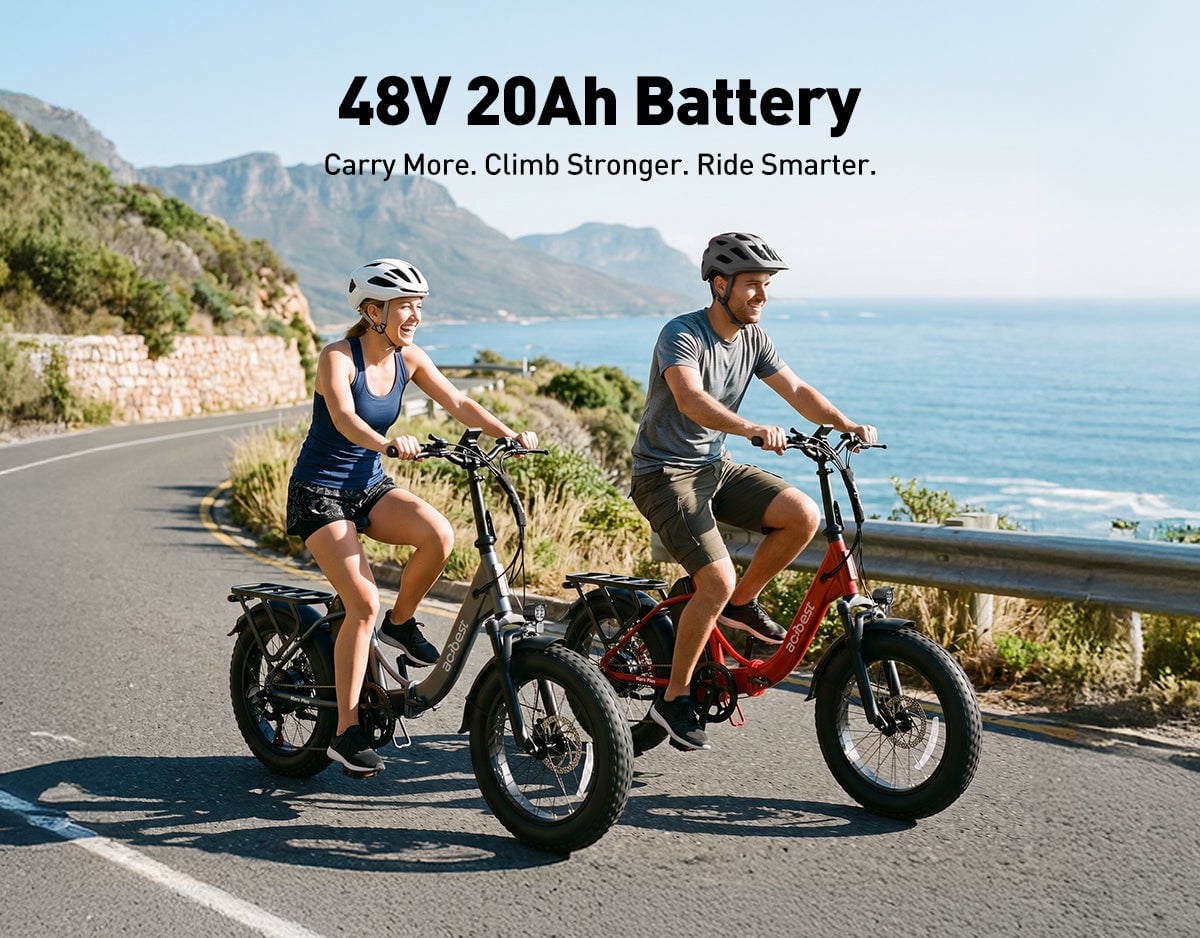 Two people riding compact foldable ebikes on a scenic coastal road with mountains