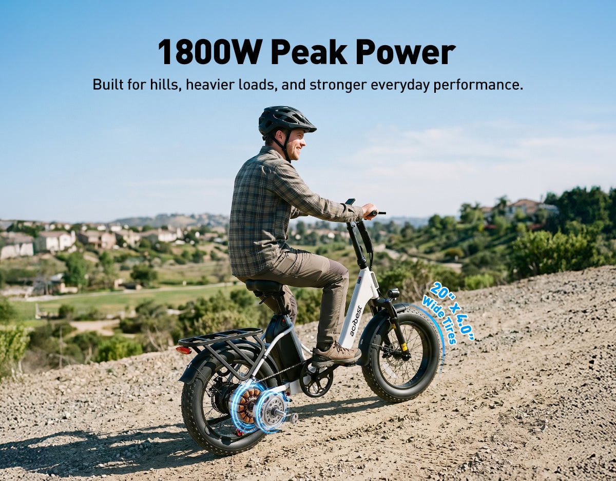 Man riding a compact white ebike with wide tires uphill on a gravel terrain