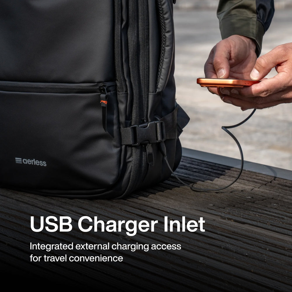 Person holding a copper-colored device with USB cable connected to a black backpack with USB charger inlet