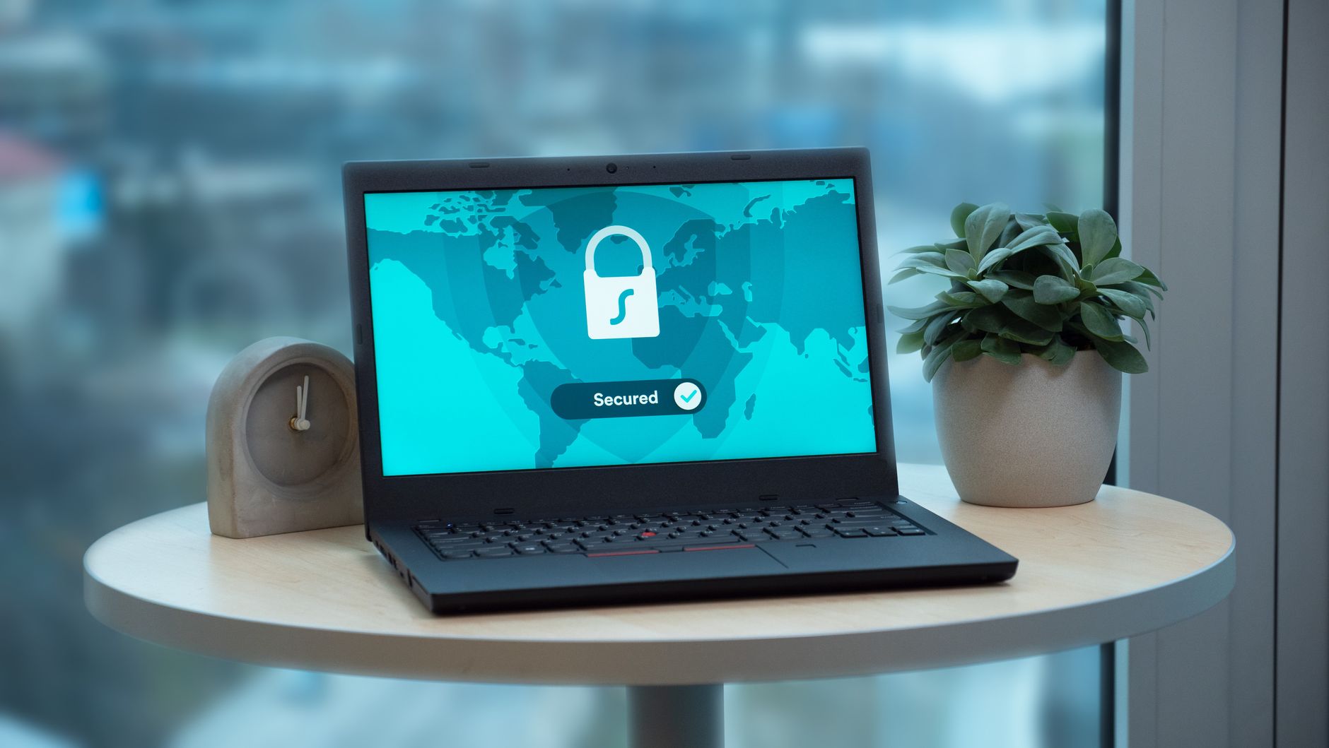 Laptop showing a world map with a padlock icon and 'Secured' status indicator on screen