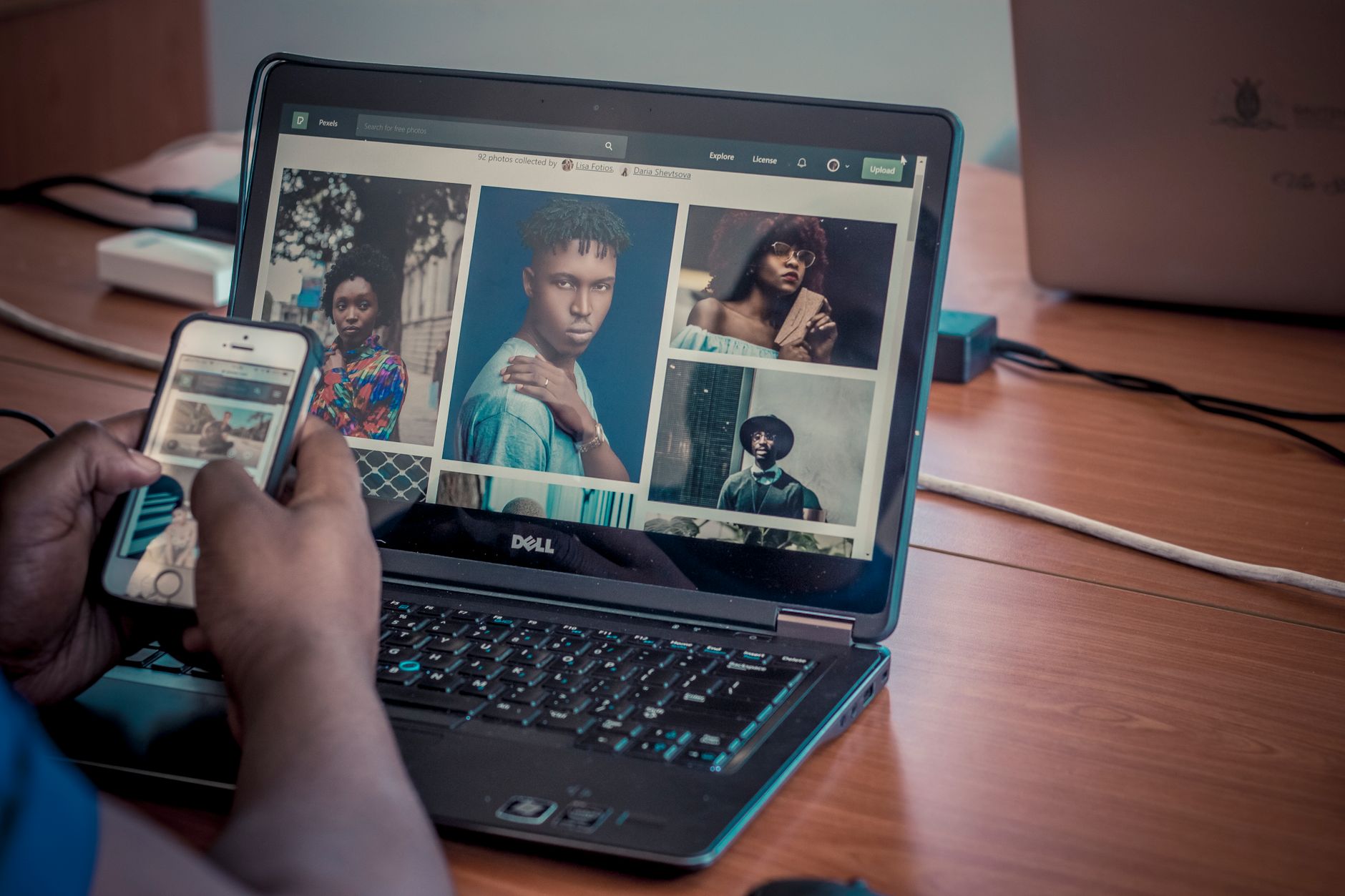 Ręce trzymające smartfona i laptopa wyświetlającego galerię portretów fotograficznych