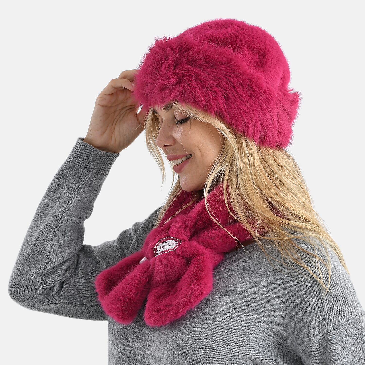 Woman in profile wearing hot pink faux fur hat and scarf, holding brim of hat with hand raised